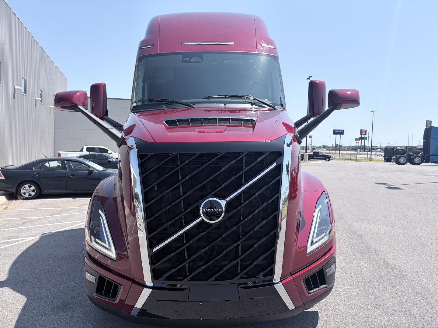 Front view of a red Volvo VNL64T860 truck showing large black grille with chrome accents and Volvo emblem, headlights, and elevated sleeper cabin.