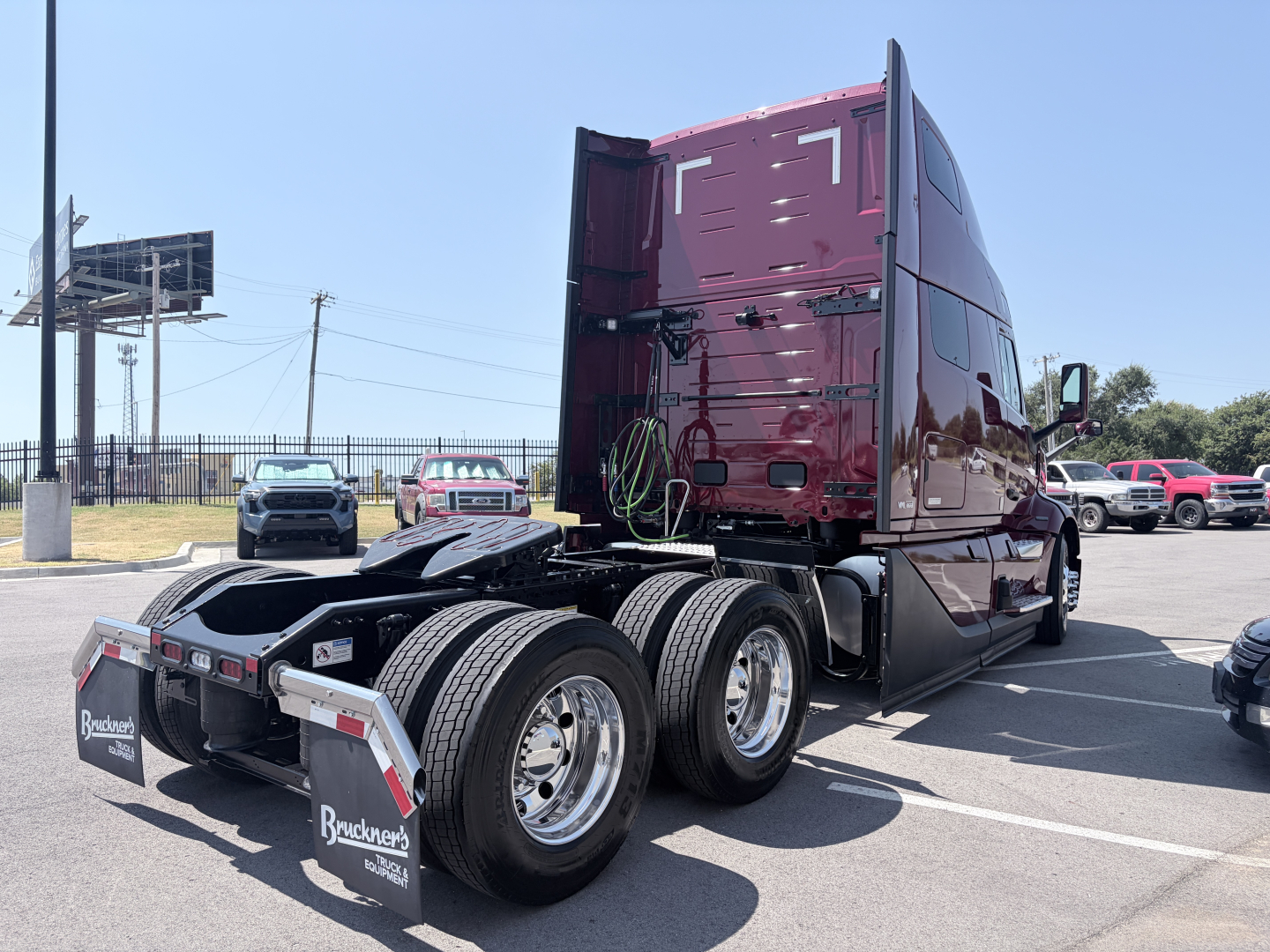 Volvo VNL64T860 truck tractor rear and side view showing fifth wheel and dual rear axles with chrome wheels and maroon cab; no visible text besides Brackeen's logo on mudflaps.