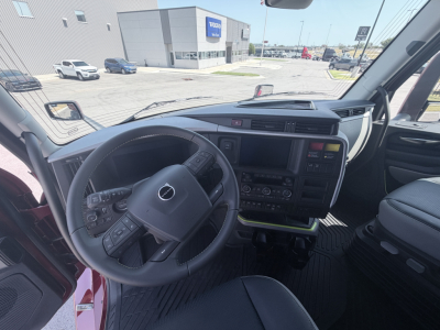Volvo truck cab interior with steering wheel, dashboard, and center touchscreen. Visible on the console: various controls, gear selector, and a hooded instrument cluster.