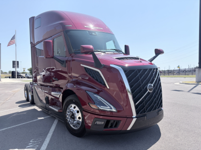 Volvo VNL64T860 tractor truck in maroon showing front grille and headlights, side view mirrors, chrome wheels; cab-over design with aerodynamic features.