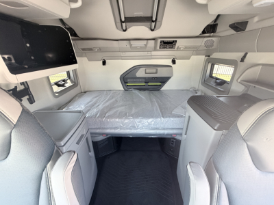 Interior cab view of 2027 Volvo VNL64T860 sleeper showing bed area and side storage compartments.