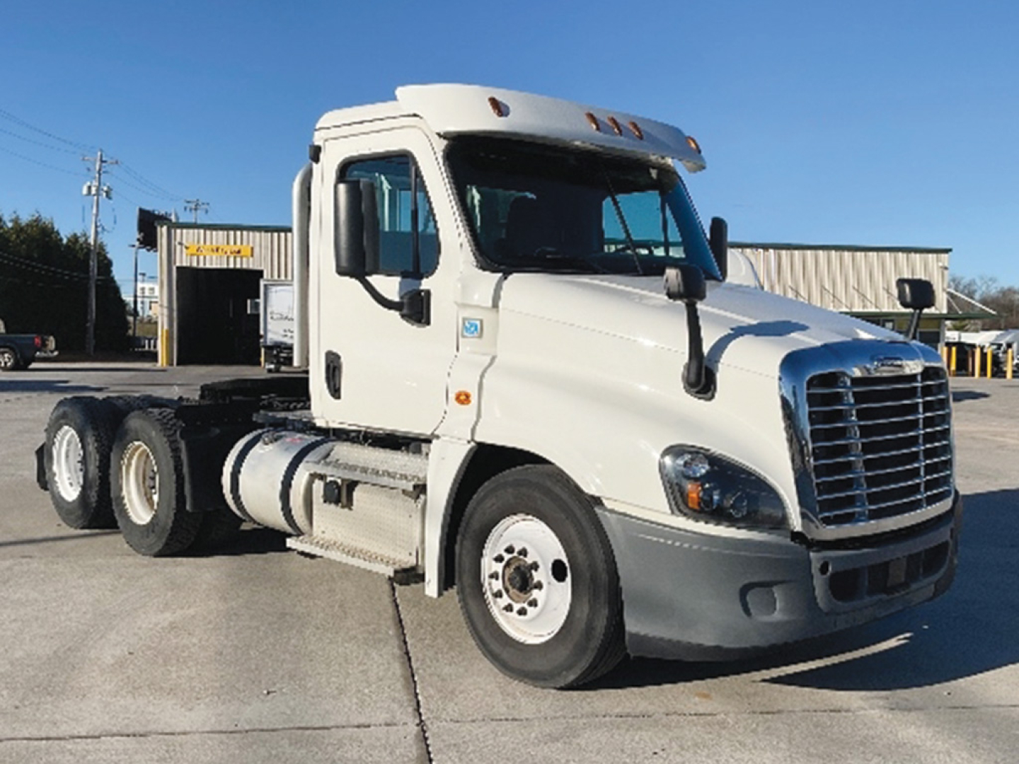 Conventional daycab truck showing Freightliner Cascadia125 with sleeper cab, side view of white tractor with three axles and dual rear wheels.