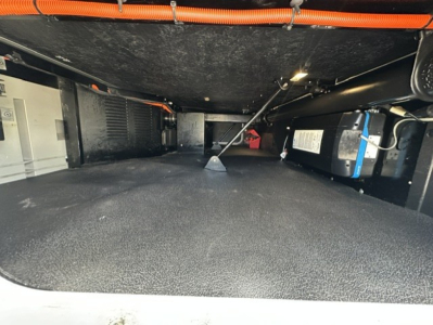 Interior storage area of a 2023 Kenworth T680 underbelly clearance showing storage bin and cables.