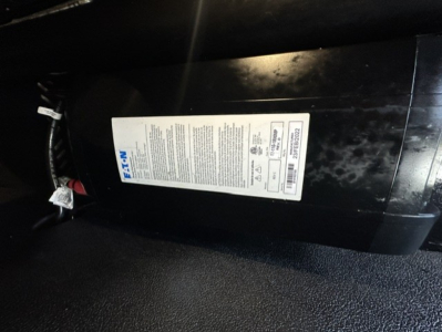 Kenworth T680 dash area showing a white label with Eaton branding and technical text, battery cables nearby.