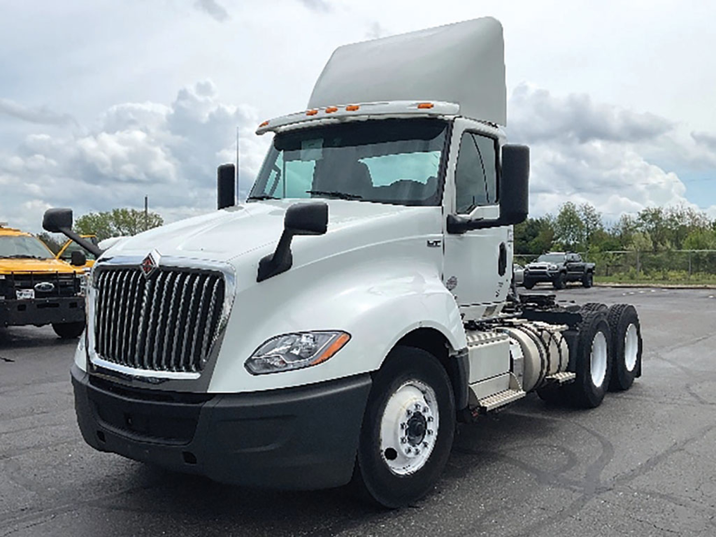 White 2019 International LT625 conventional daycab truck, hood open, dual rear axles, front grille with International emblem, black bumper, side mirrors, fuel tanks, and exposed engine area.