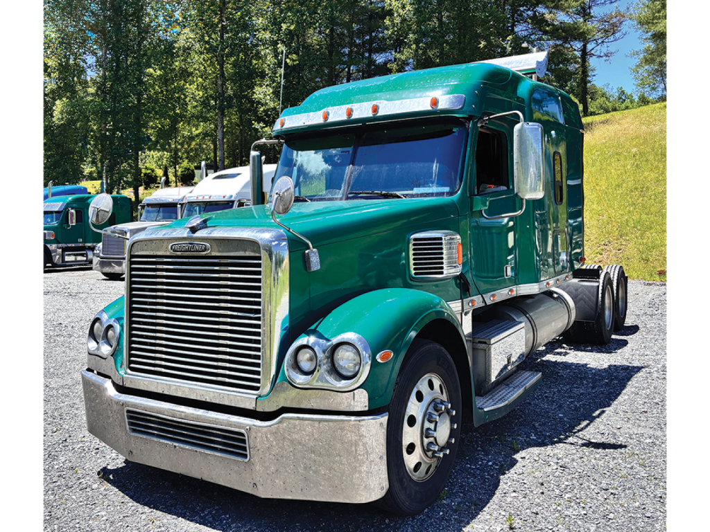 Truck image: green Freightliner Coronado semi-truck with sleeper cab, front grille, bumper, and chrome exhaust stacks visible.