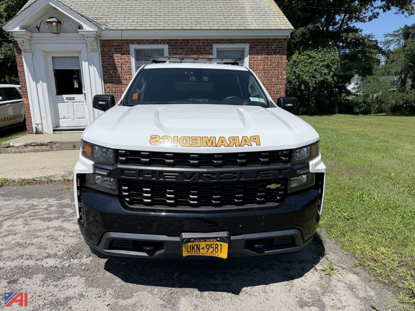 Front view of a white 2019 Chevrolet Silverado 1500 Crew Cab pickup with a cap, black grille, yellow NY license plate, and 'PARAMEDICS' decal on the hood.