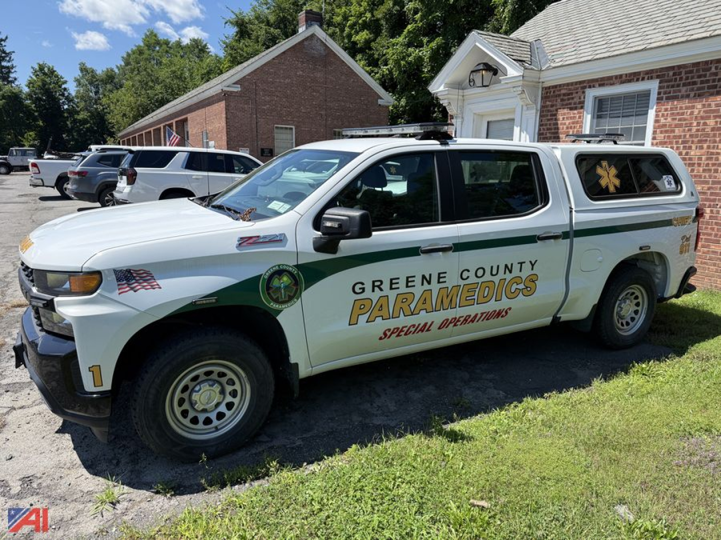Chevrolet Silverado 1500 crew cab pickup truck with Greene County Paramedics special operations livery and cap on bed, side view.