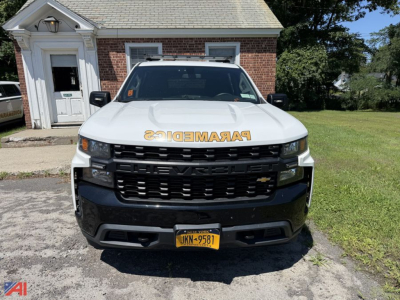Front view of a white 2019 Chevrolet Silverado 1500 Crew Cab pickup with a cap, black grille, yellow NY license plate, and 'PARAMEDICS' decal on the hood.