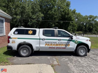 Side view of a white 2019 Chevrolet Silverado 1500 Crew Cab pickup with a Green County Paramedics Special Operations cap emblem and green stripe along the body.