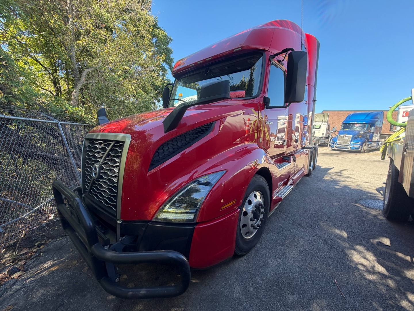 Volvo VNL64T760 sleeper tractor in red with black front bumper and large grille, side view, parked on lot.