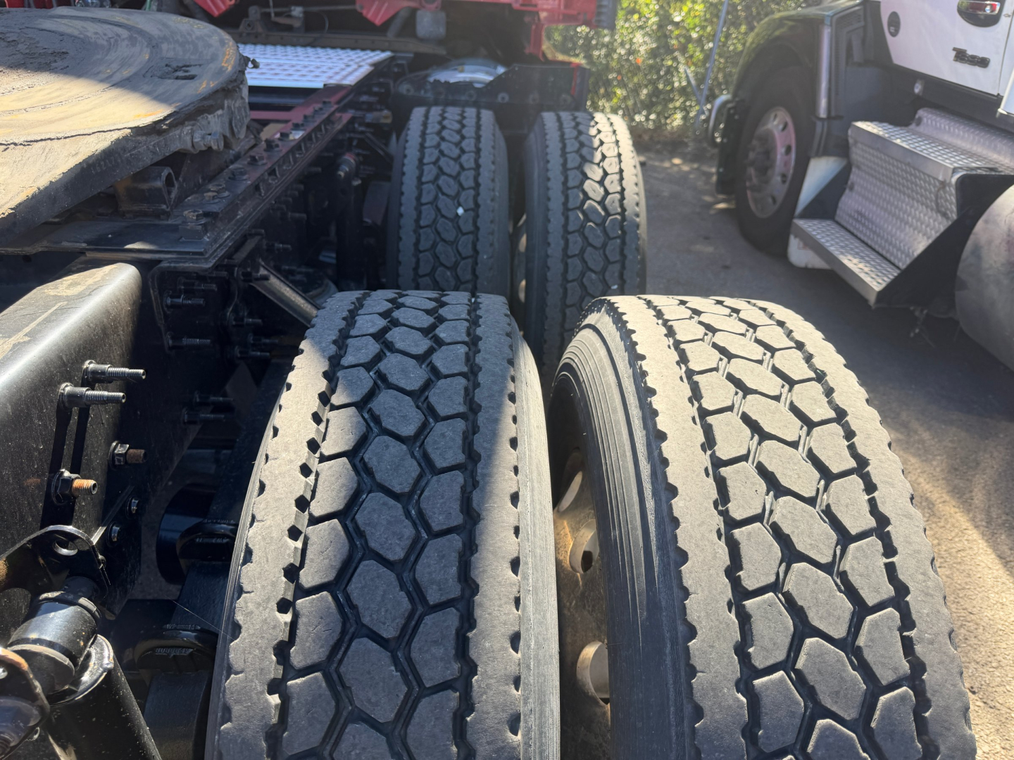 Truck tandem axles with dual rear tires and hexagonal tread pattern visible; part of the chassis and suspension visible.