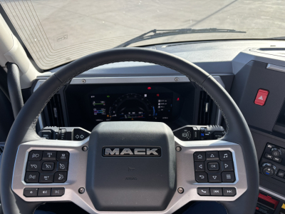 Mack AN64T truck interior steering wheel view with dashboard gauges and control panels on both sides.