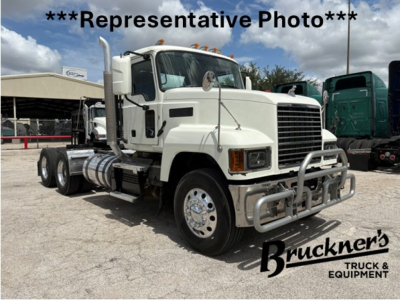White 2020 Mack PI64T conventional daycab truck in a lot with other trucks, showing front grille, bumper guard, dual exhaust stacks, and chrome wheels.