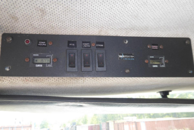 Panel showing switches and gauges on Freightliner FL70 dash area with labels for compartments and lights.