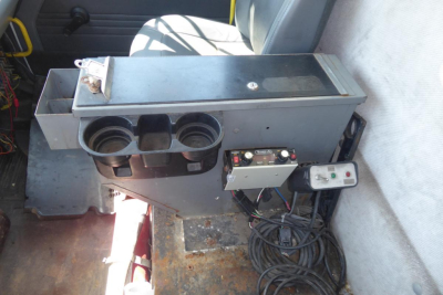 Truck interior showing snow plow control box and cup holders with wiring harness, metal box, and controls.