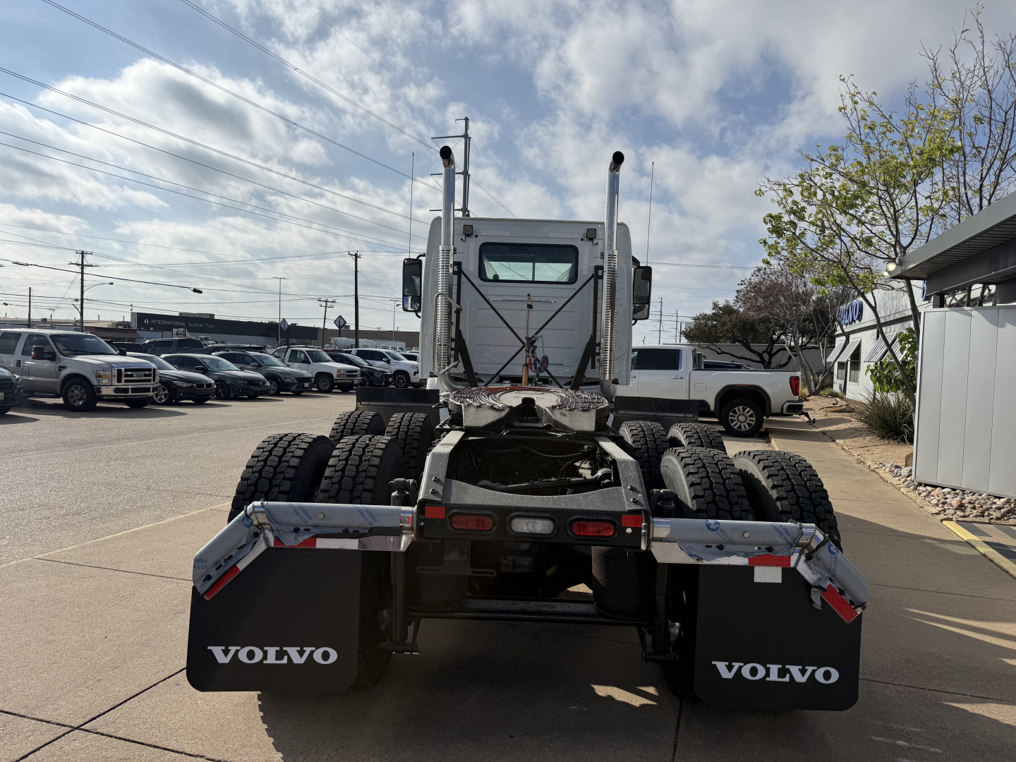 Volvo VHD64FT300 tractor rear view showing dual rear axles, fifth wheel, and Volvo mud flaps with white Volvo logo.