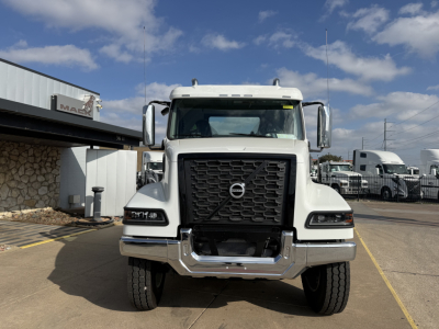 Volvo VHD64FT300 truck front view in white with large black grille and chrome bumper, daytime dealership lot background.