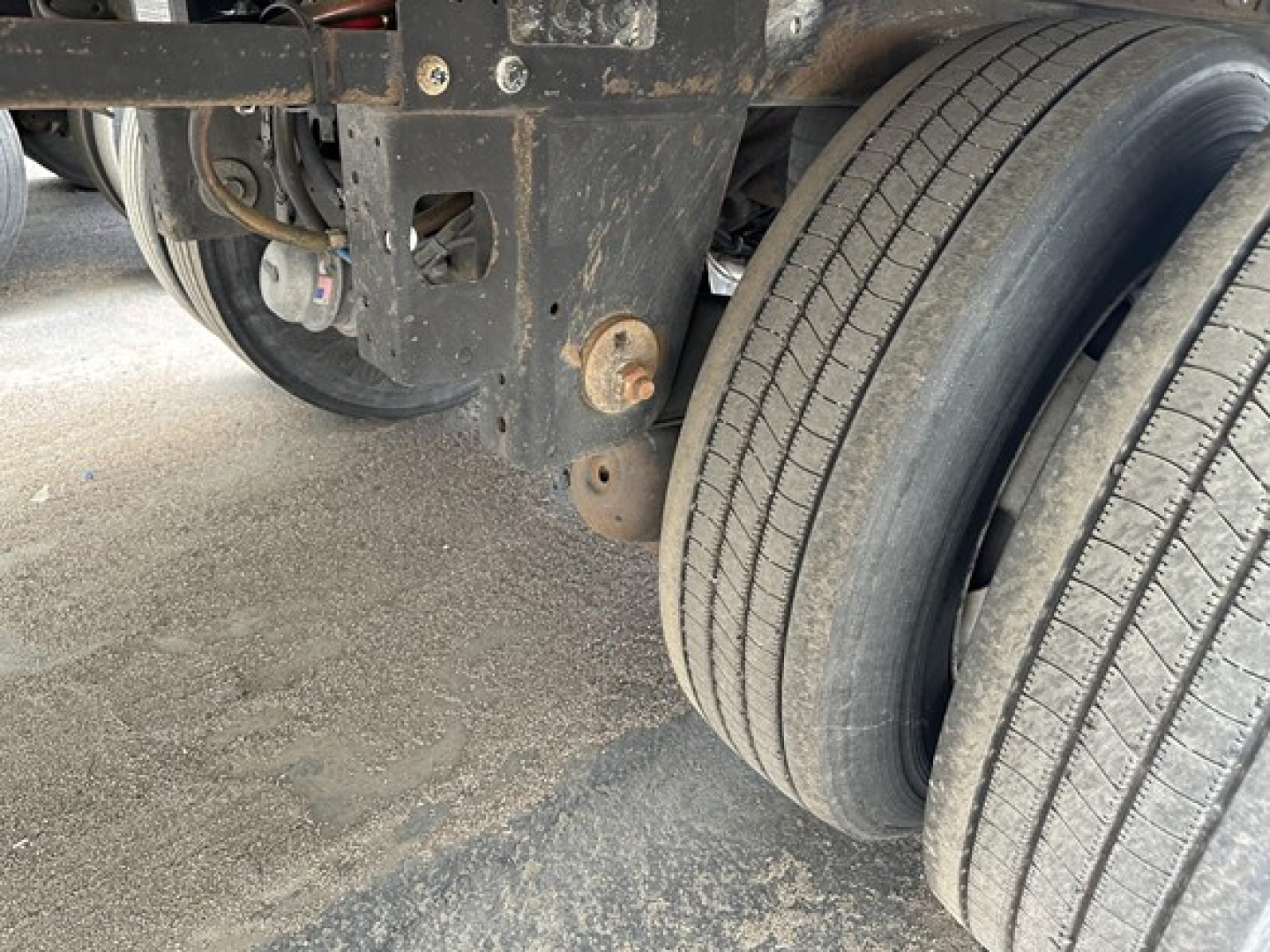 Dual rear tires and undercarriage of a utility trailer showing wheel assembly, frame, and suspension components.