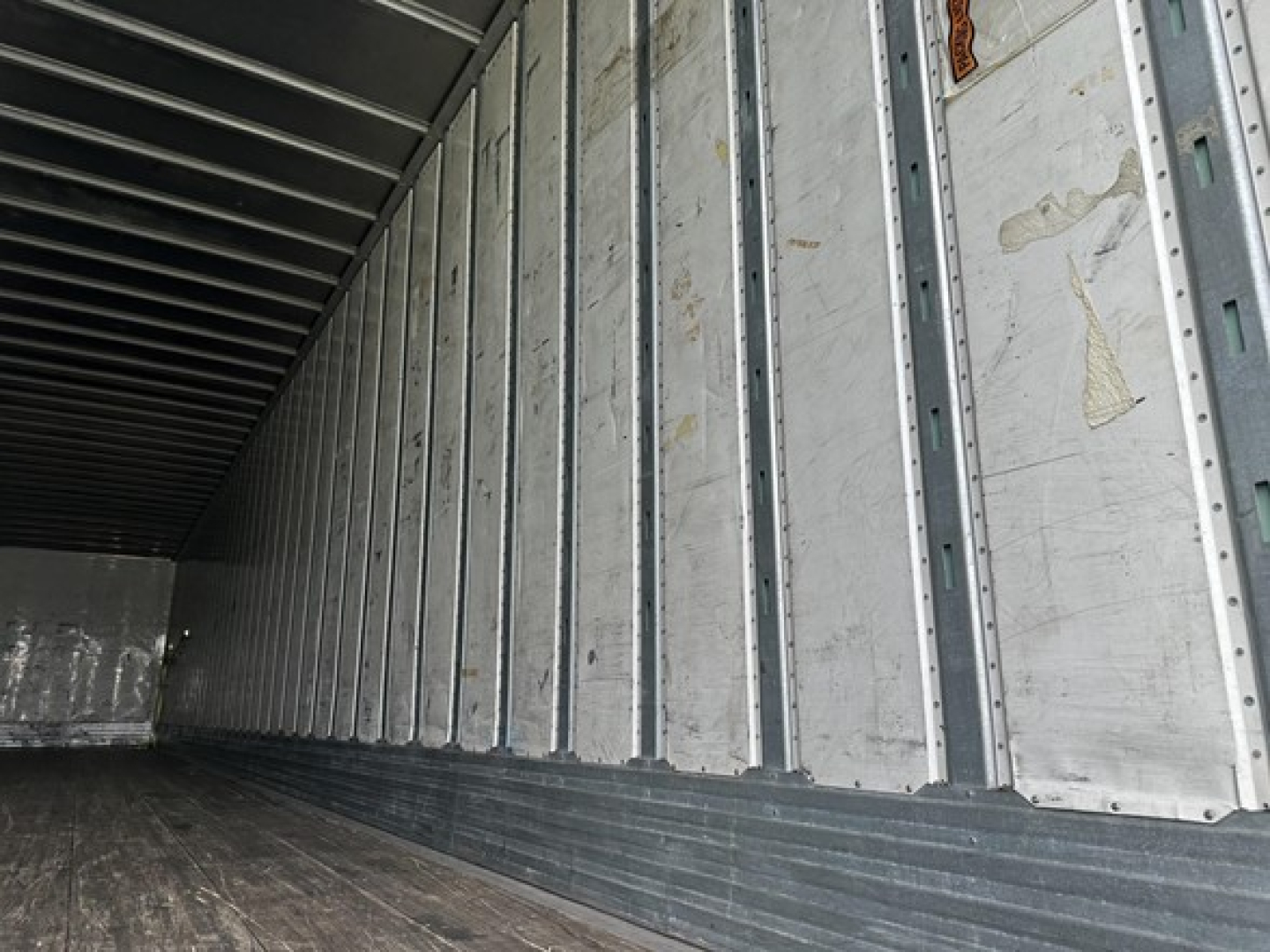 Trailer interior showing vertical metal studs and wooden floor in a Utility 4000D-X trailer, empty cargo area.
