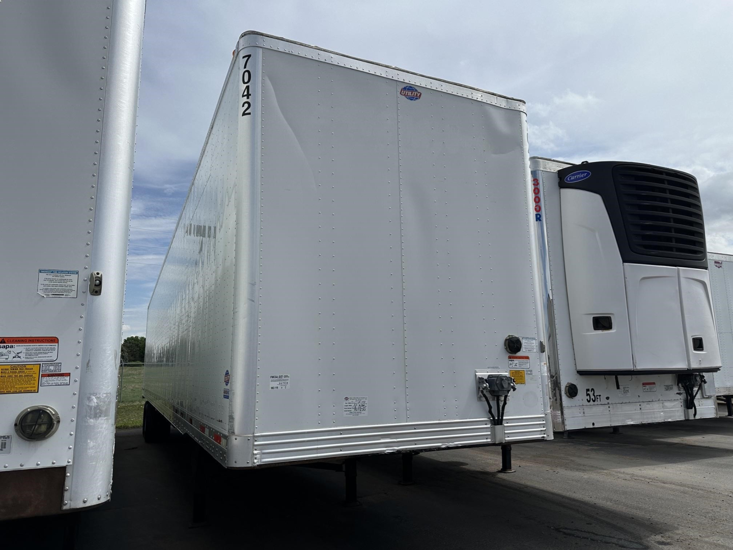 Utility 4000D-X trailer in a lot, rear view showing doors and nose area with ramp, VIN sticker area and registration numbers faintly visible.