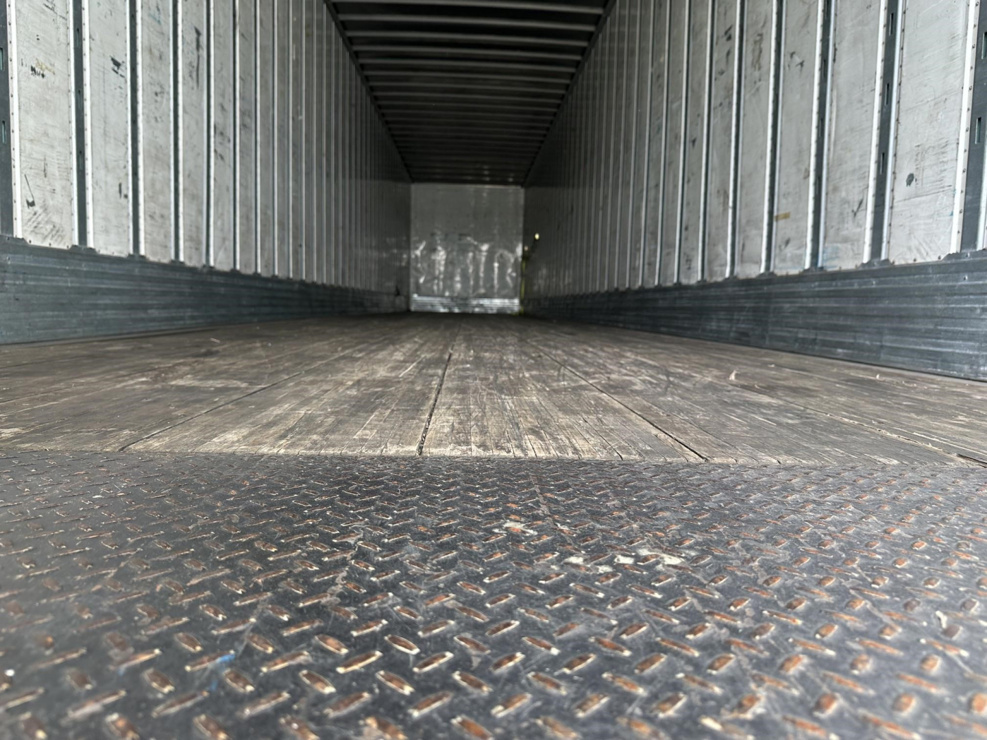 Empty Utility trailer interior with metal walls and wood floor, Diamond plate at the threshold.