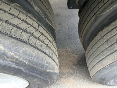 Dual trailer tires and mud between wheels, portion of trailer undercarriage visible.