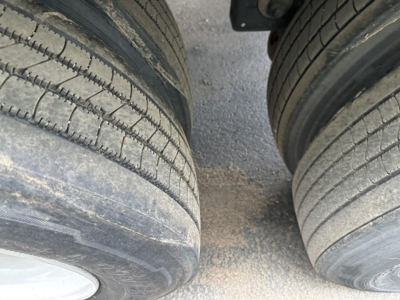 Two rear tires of a Utility 4000D-X trailer showing tread lines and gravel between wheels.
