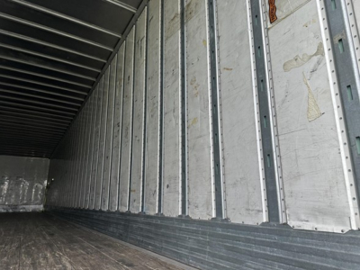 Trailer interior showing vertical metal studs and wooden floor in a Utility 4000D-X trailer, empty cargo area.