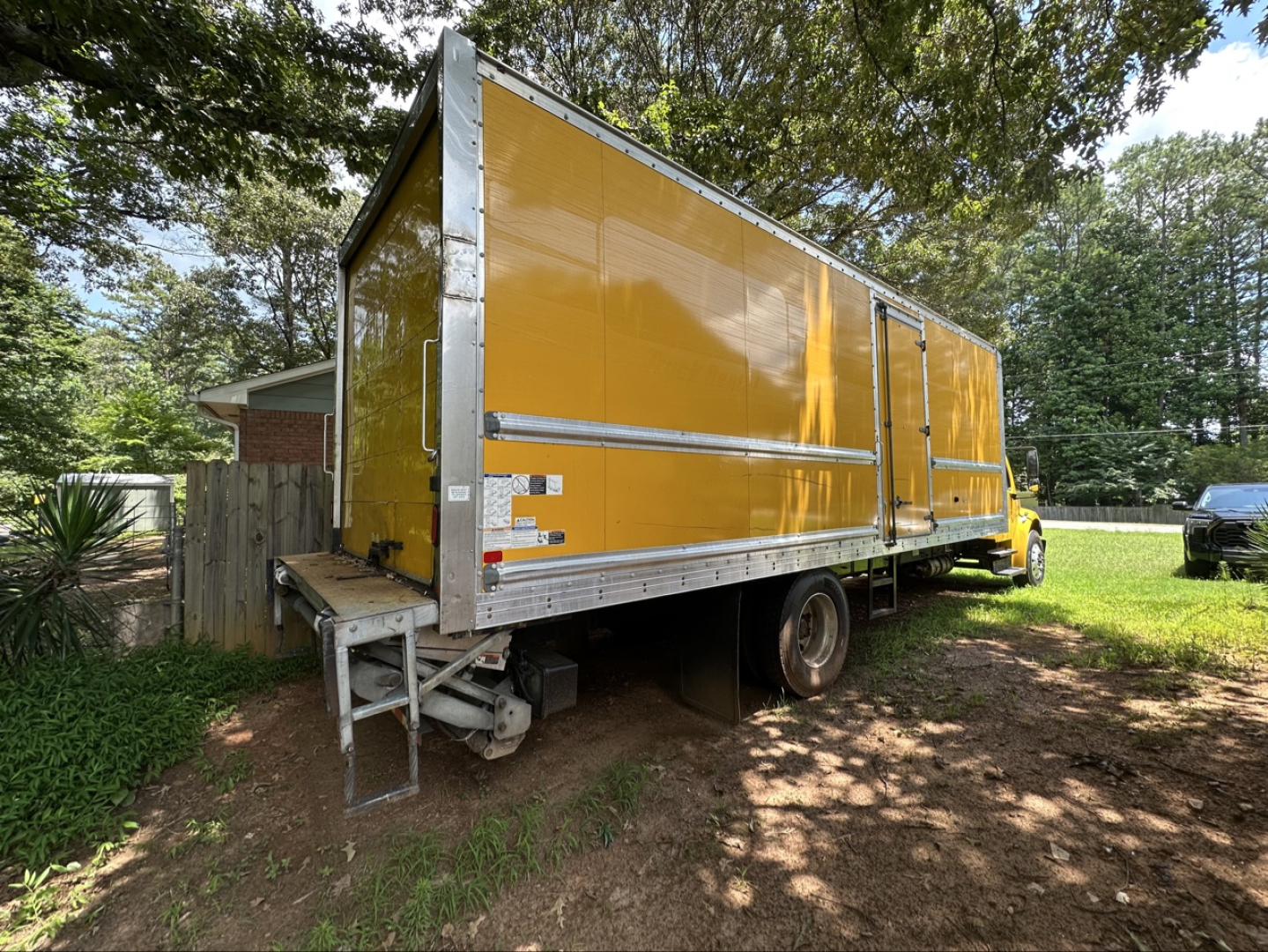 2019 Freightliner M2 106 box truck with yellow cargo box, side door, rear stairs, and VIN tag not visible.