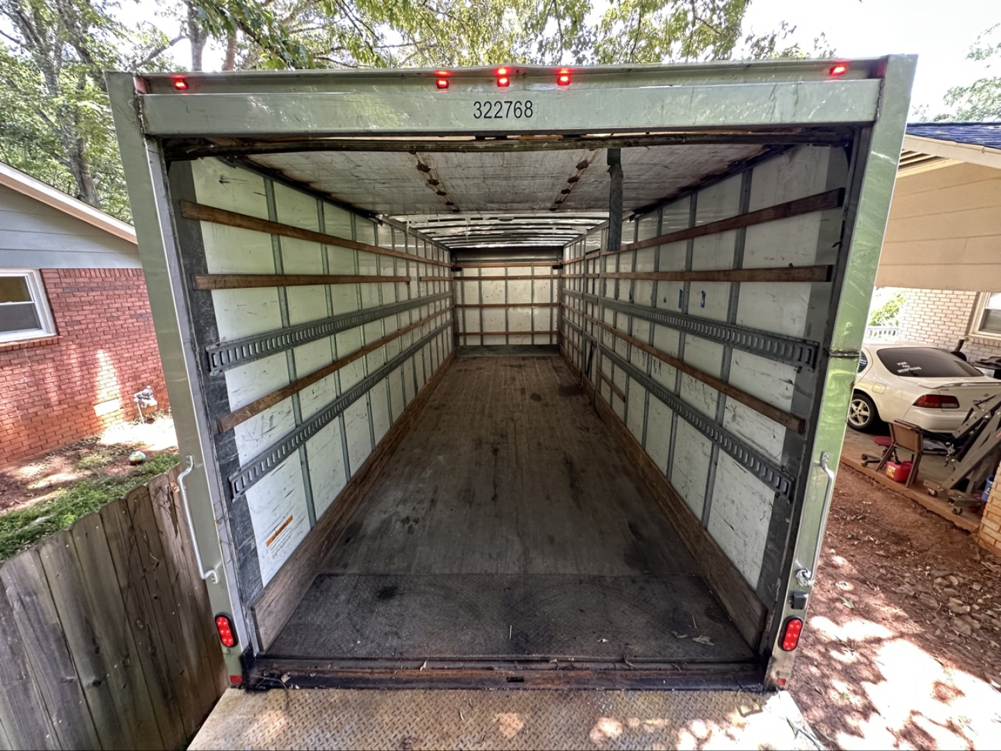 Box truck cargo area of a 2019 Freightliner M2 106 with empty interior, metal side rails, rear doors open, wood and metal floor, VIN code plate visible.