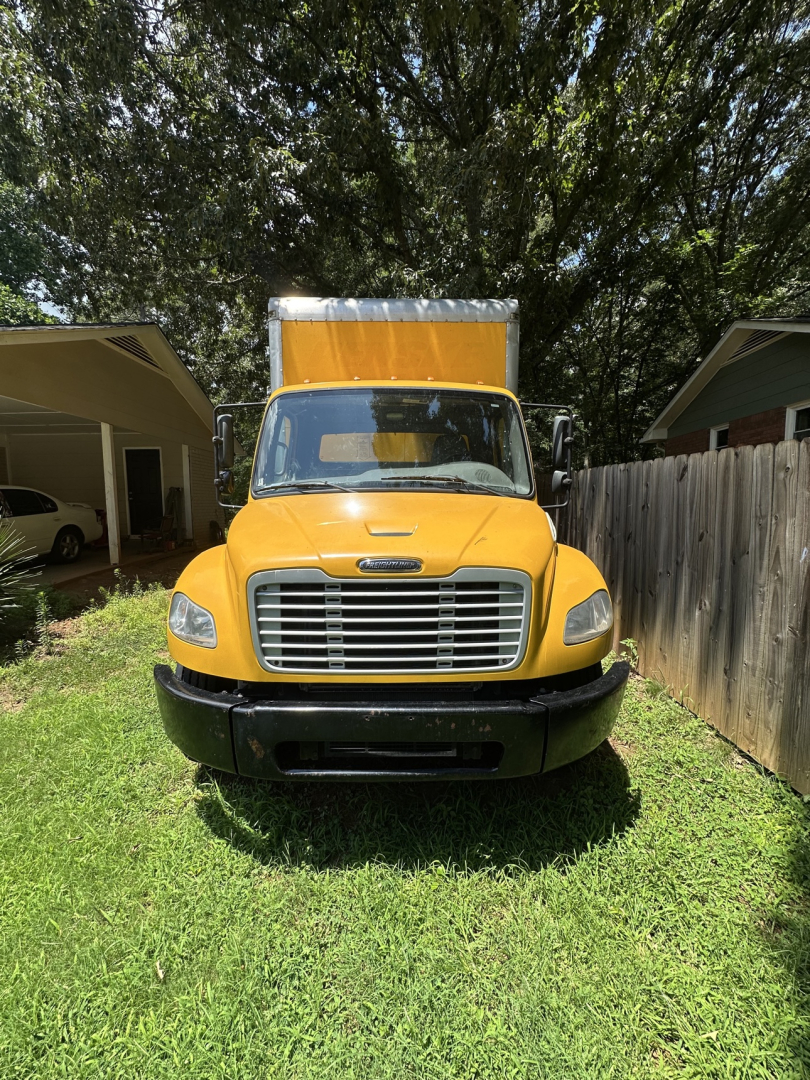Front view of a yellow 2019 Freightliner M2 106 box truck with a large rectangular cargo area, black bumper, and grille.