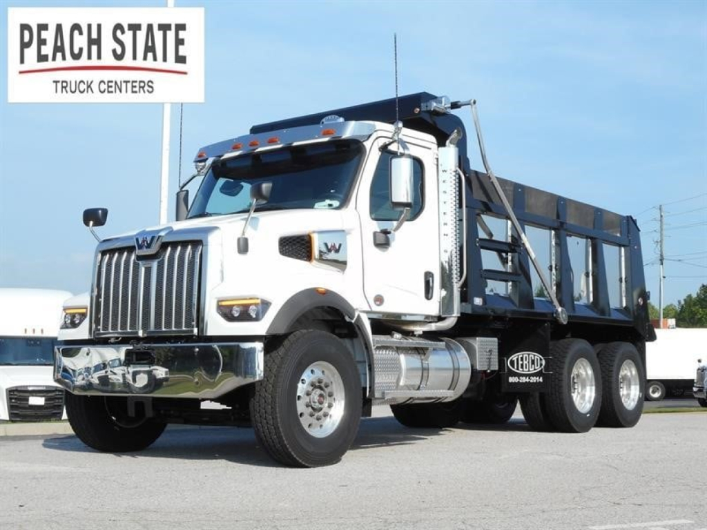 White Western Star 47X dump truck in service bay with chrome bumper and black dump bed, Peach State Truck Centers sign in background.