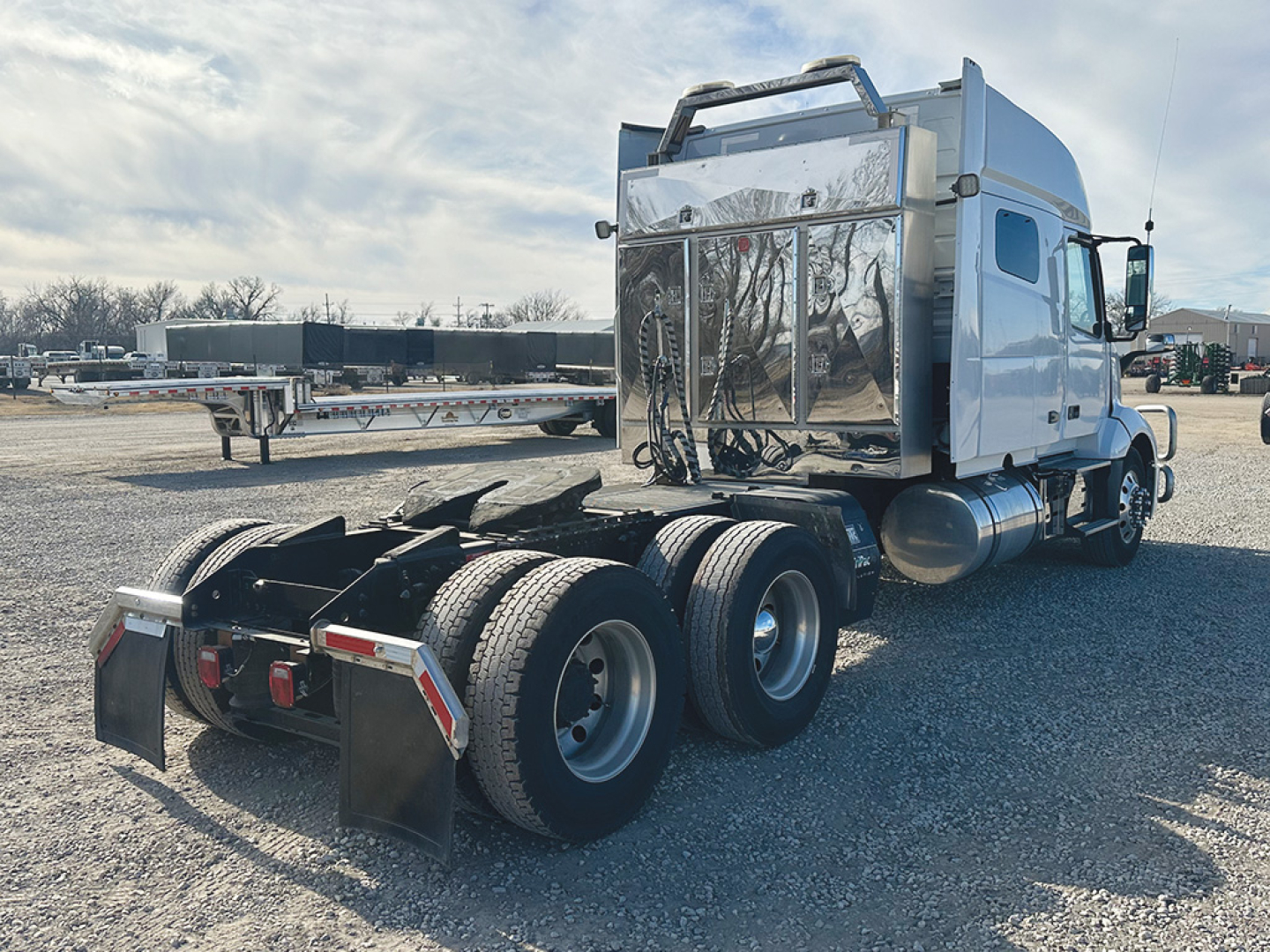 2022 Volvo VNL 740 tractor rear view showing third axle, fuel tanks, and polished chrome toolbox area.