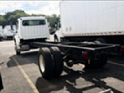 Freightliner M2 106 cab and chassis chassis frame and rear dual wheels visible in a parking lot.