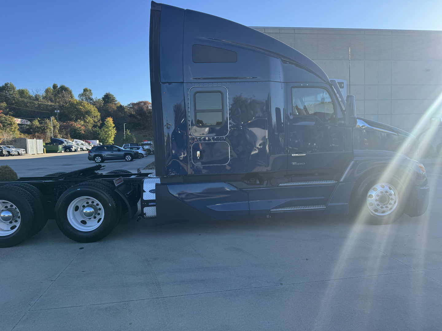 Kenworth T680 tractor side view showing sleeper cab and dual rear axles with glossy dark paint.