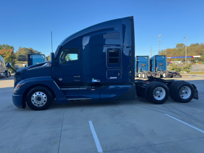 Kenworth T680 side view near-cab showing sleeper compartment and wheels, blue truck in a dealership lot.