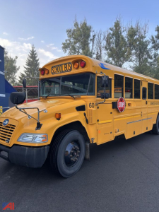 School bus side view showing stop sign and yellow body with black tires and blue trim, 60 on front fender.