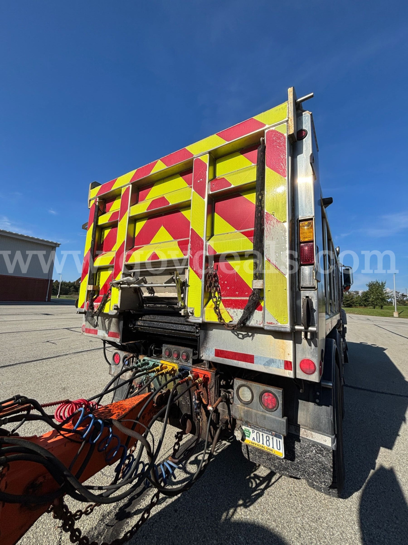 Rear view of 2013 Mack GU Granite plow truck showing reflective chevron pattern and hydraulic hose connections.