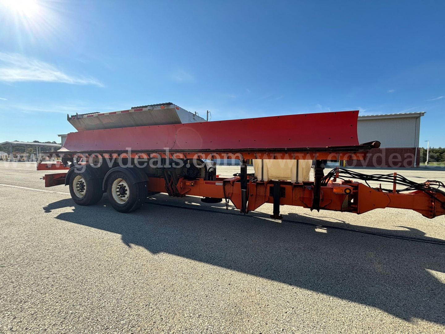 Mack GU Granite plow truck trailer showing red/silver plow blade on orange chassis and dual rear axles.
