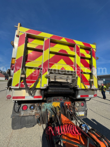 Rear view of a 2013 Mack GU (Granite) GU713 plow truck showing high-visibility chevron pickup in yellow and red, tow hoses, and rear lights.