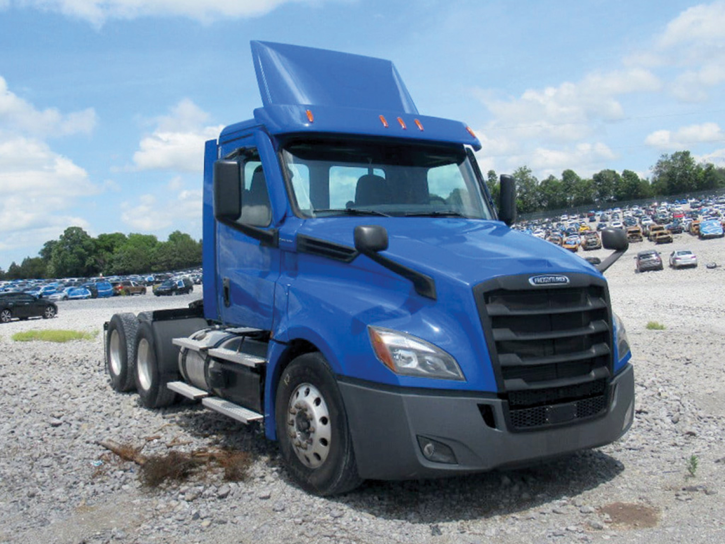 Freightliner Cascadia126 daylight view showing blue semi tractor with sleeper cab, front grille, dual rear axles, in a used truck lot.