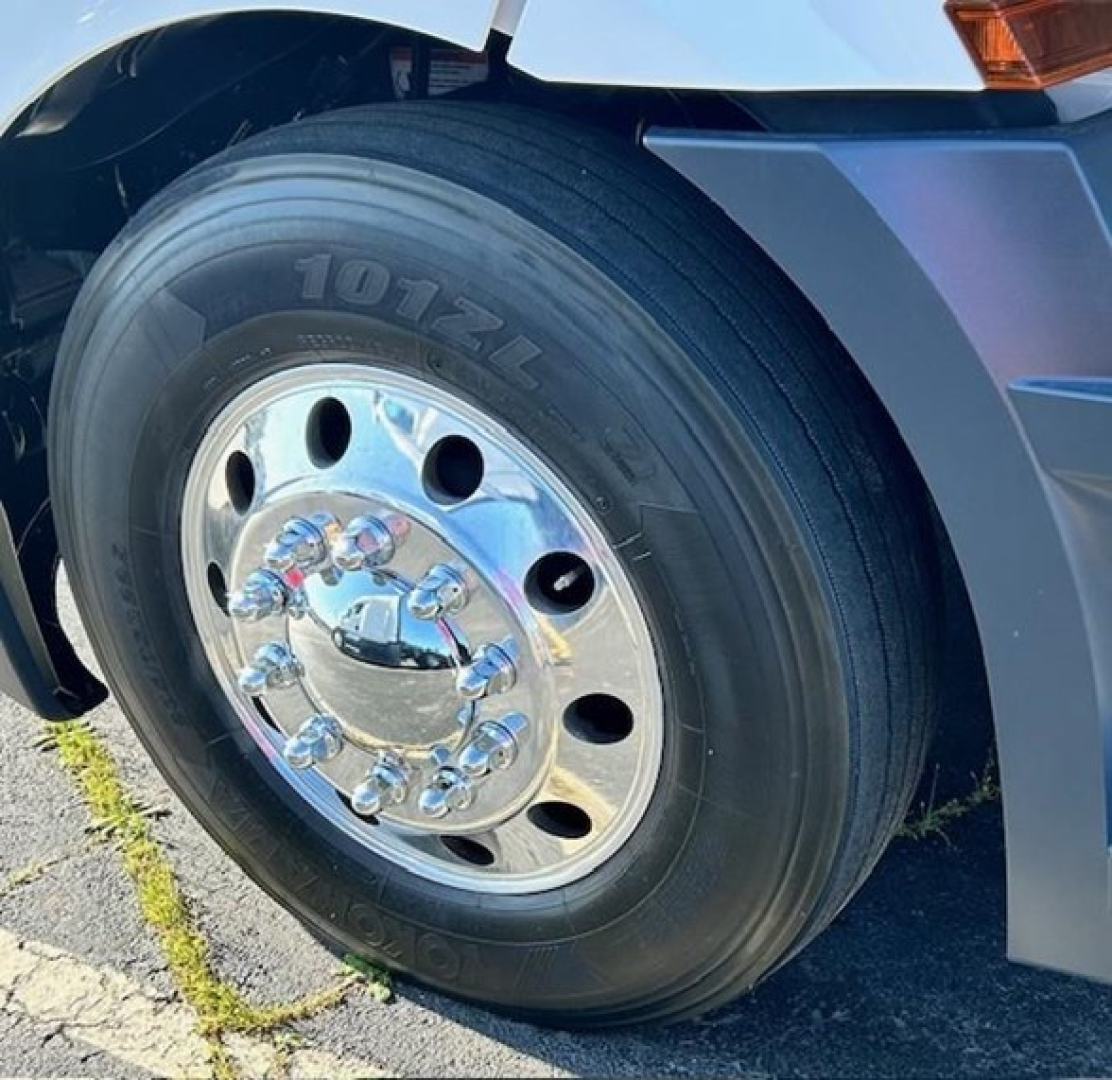 Truck wheel close-up showing a large chrome hubcap and 1012L tire on Freightliner Cascadia 126 front wheel arch