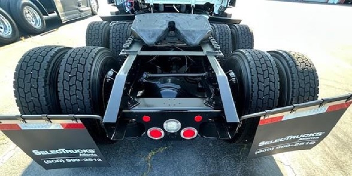 Rear view of a 2023 Freightliner Cascadia 126 tractor showing dual rear axles and suspension, with mud flaps and dual exhausts visible.