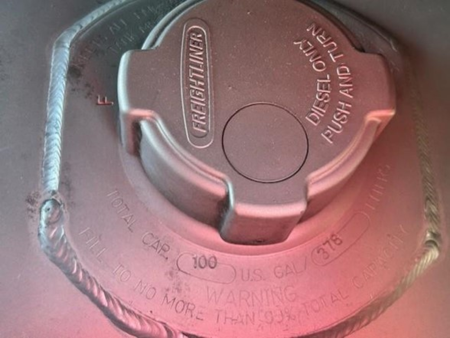 Diesel fuel cap on Freightliner Cascadia 126 showing DEF/return vent and warning text.