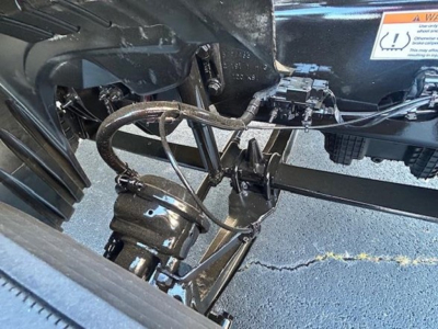 Truck front chassis area showing hydraulic lines and steering component in a Freightliner Cascadia 126 undercarriage.
