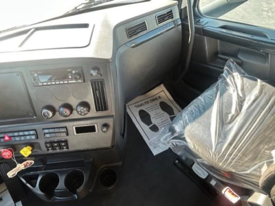 Interior of a 2023 Freightliner Cascadia 126 truck cab showing dashboard controls and driver seat wrapped in plastic.