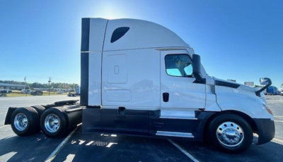 Truck side view showing a white Freightliner Cascadia 126 sleeper tractor with black lower panels and dual rear axles.