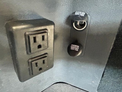 Electrical outlet panel and power outlet on Freightliner Cascadia dash area showing dual-prong outlet and 12V power plug cover.