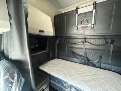 Interior sleeper cab of a Freightliner Cascadia showing bunk area with net storage and control panels.